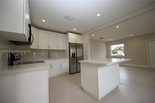 kitchen featuring tasteful backsplash, visible vents, stainless steel refrigerator with ice dispenser, stove, and a sink