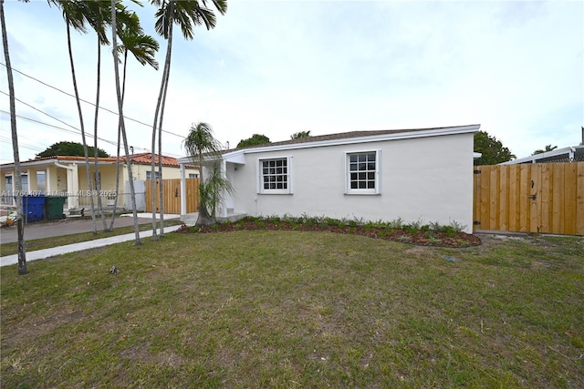 view of front facade featuring stucco siding, a front lawn, and fence