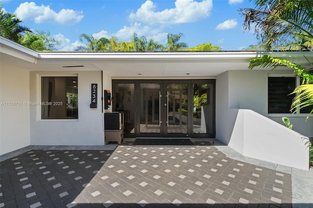 view of exterior entry with a patio, french doors, and stucco siding