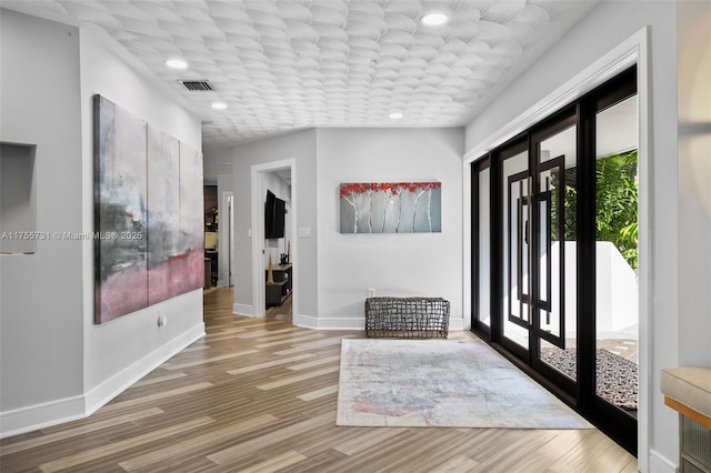 entrance foyer with wood finished floors, french doors, visible vents, and baseboards