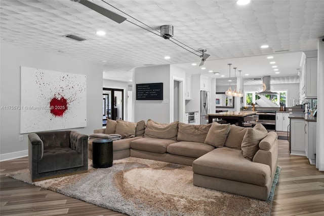 living area featuring recessed lighting, visible vents, and wood finished floors