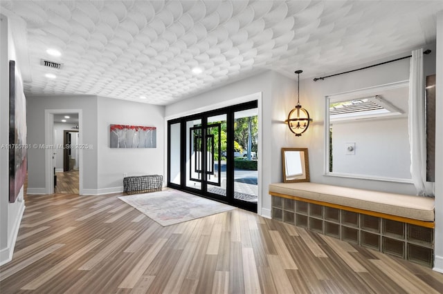 foyer entrance with visible vents, baseboards, wood finished floors, and french doors