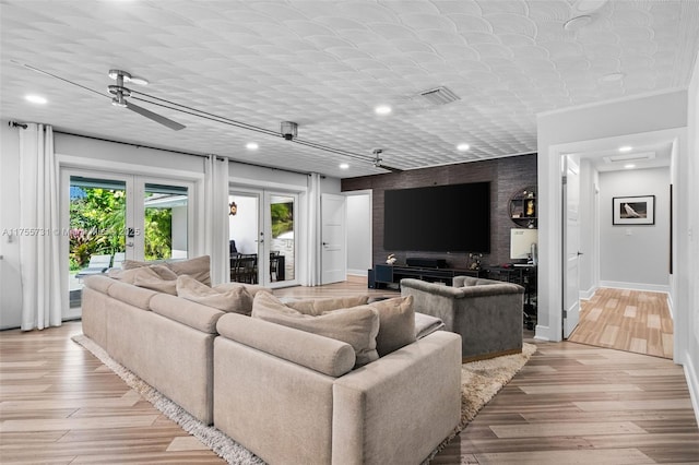 living room featuring wood finished floors, recessed lighting, french doors, baseboards, and an accent wall