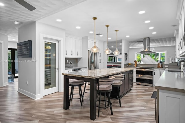 kitchen with island exhaust hood, a sink, white cabinets, stainless steel refrigerator with ice dispenser, and a center island