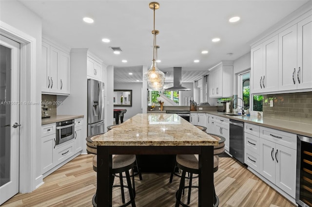 kitchen featuring recessed lighting, range hood, a sink, and appliances with stainless steel finishes