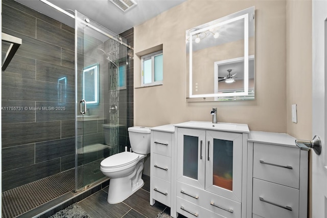 bathroom with visible vents, a stall shower, toilet, and vanity