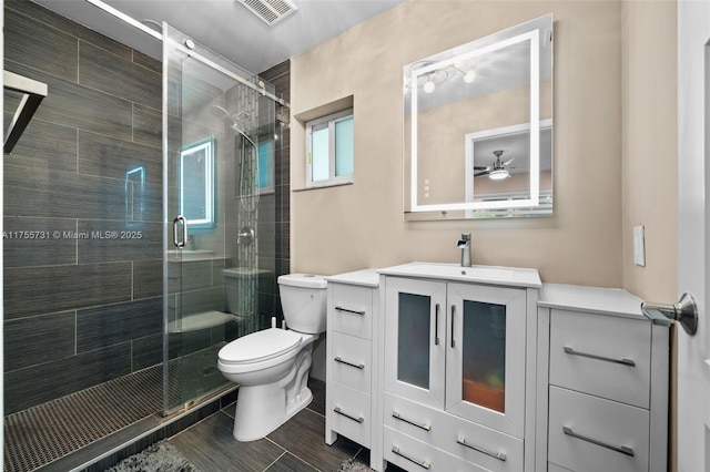 bathroom featuring visible vents, a stall shower, toilet, and vanity