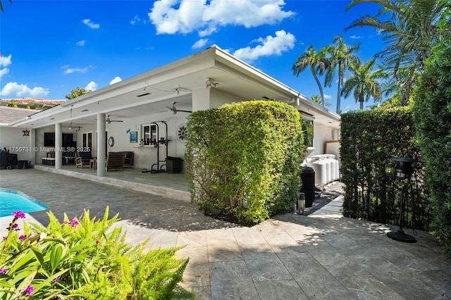 back of property featuring stucco siding, an outdoor pool, a ceiling fan, and a patio