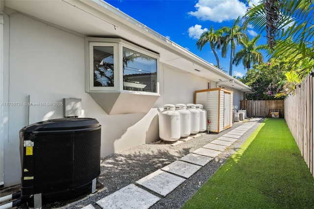 view of home's exterior with a fenced backyard, a lawn, central AC, and stucco siding