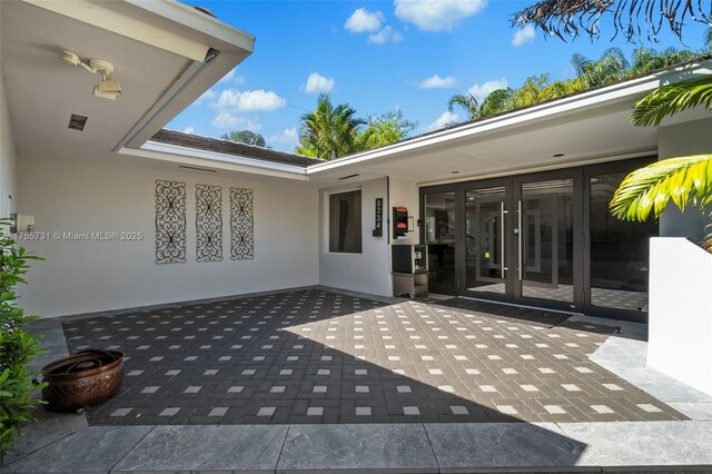 view of exterior entry featuring stucco siding, a patio, and french doors