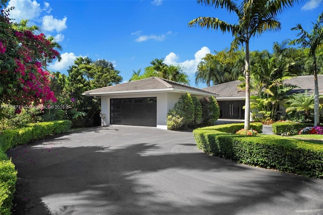 view of front of property with a tile roof, an attached garage, driveway, and stucco siding