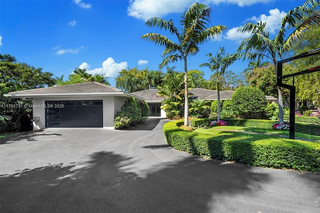 ranch-style house with aphalt driveway, stucco siding, a tiled roof, and an attached garage