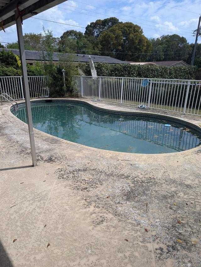 outdoor pool featuring a patio area and fence