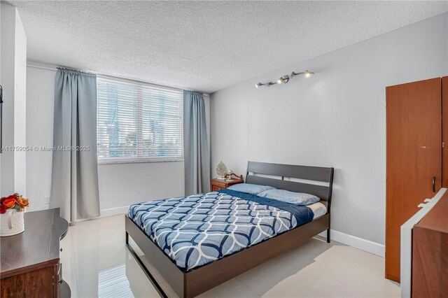 bedroom with a textured ceiling and baseboards