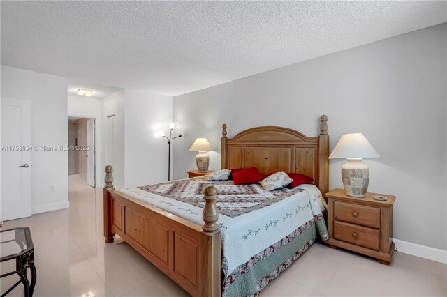 bedroom with light tile patterned flooring, a textured ceiling, and baseboards