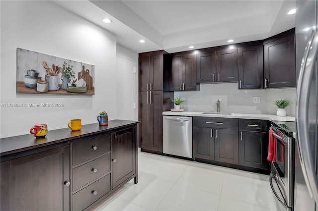 kitchen featuring backsplash, dark brown cabinetry, recessed lighting, stainless steel appliances, and a sink