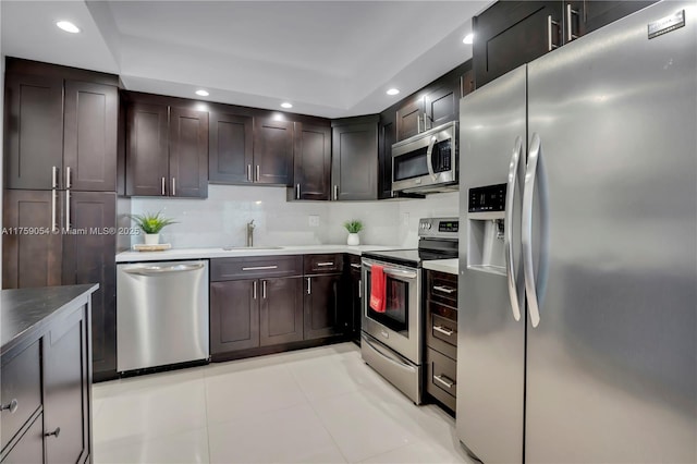 kitchen featuring dark brown cabinets, light tile patterned floors, recessed lighting, stainless steel appliances, and a sink