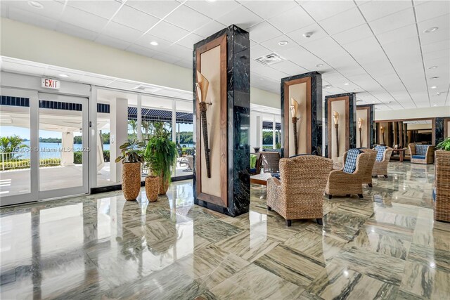 building lobby featuring a paneled ceiling, a water view, and recessed lighting