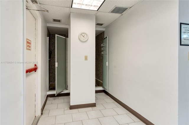 interior space featuring a drop ceiling, visible vents, and baseboards