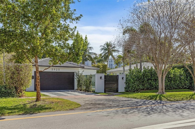 view of front of property with an attached garage, fence, stucco siding, driveway, and a gate