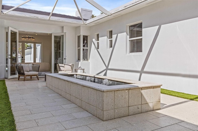 view of patio / terrace featuring french doors, a lanai, and an outdoor fire pit