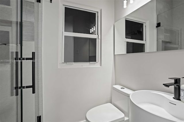 bathroom featuring a sink, toilet, and a stall shower