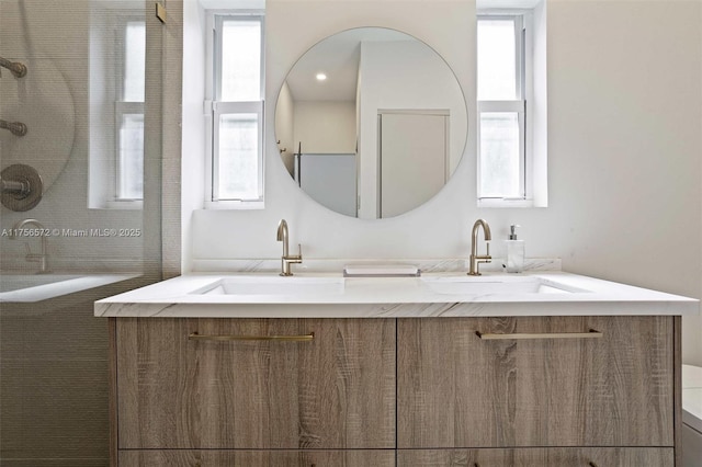 bathroom with a sink, tiled shower, and double vanity