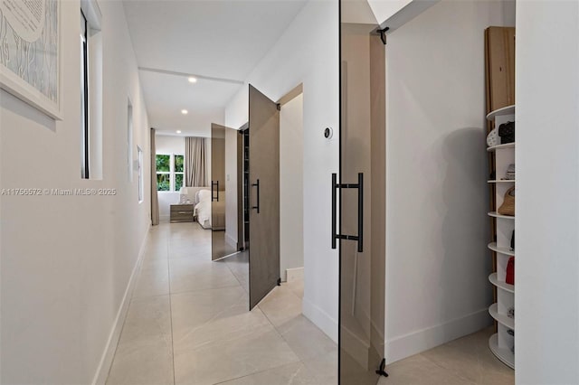 corridor with recessed lighting, a barn door, and baseboards