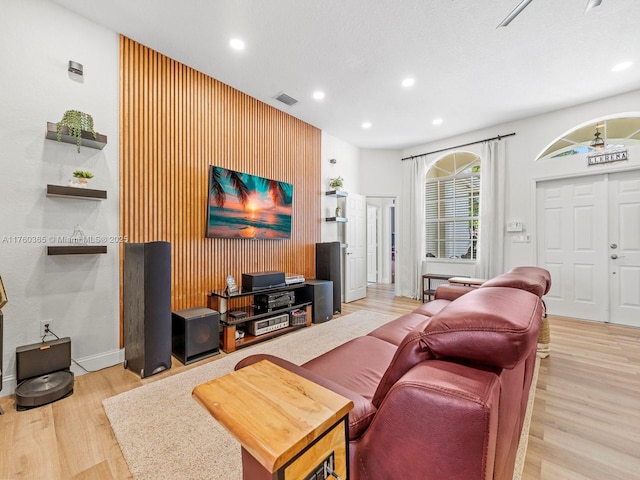 living room with visible vents, recessed lighting, light wood-type flooring, and an accent wall