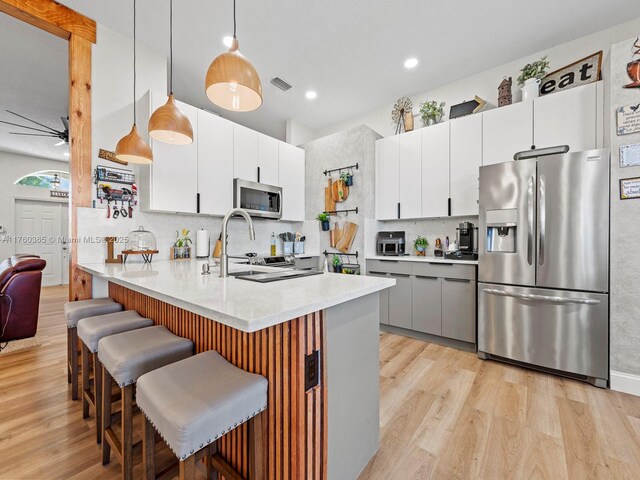 2430 SE 5th Ct, Homestead, FL 33033 - kitchen with stainless steel appliances, light wood-style flooring, backsplash, a kitchen breakfast bar, and recessed lighting