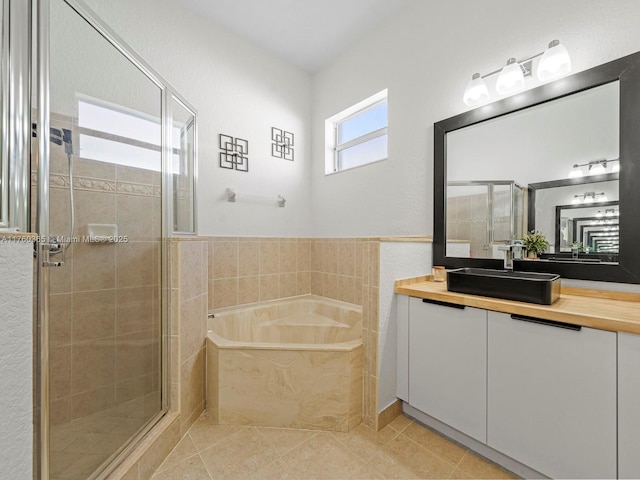 bathroom featuring tile patterned flooring, a shower stall, a bath, and vanity