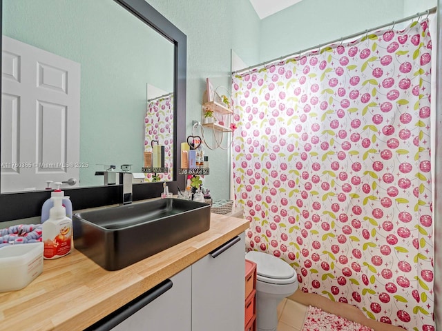 bathroom featuring vanity, a shower with curtain, tile patterned floors, toilet, and a textured wall