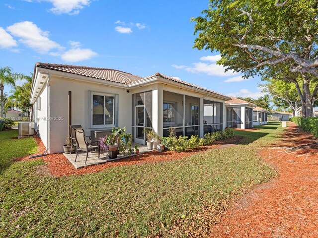 2430 SE 5th Ct, Homestead, FL 33033 - back of property with a tile roof, a lawn, a sunroom, and stucco siding