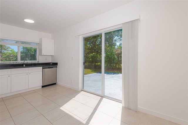 kitchen featuring dark countertops, a sink, light tile patterned floors, and stainless steel dishwasher