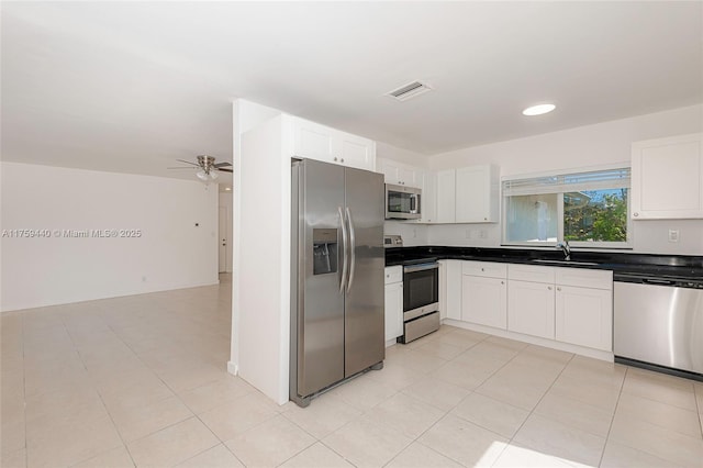 kitchen featuring dark countertops, visible vents, white cabinets, stainless steel appliances, and a sink