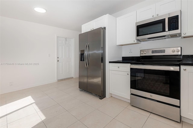 kitchen featuring light tile patterned floors, baseboards, stainless steel appliances, white cabinets, and dark countertops