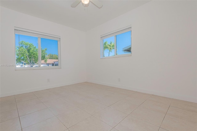 spare room featuring light tile patterned floors, a healthy amount of sunlight, and baseboards