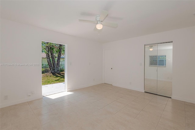 empty room featuring light tile patterned floors, ceiling fan, and baseboards