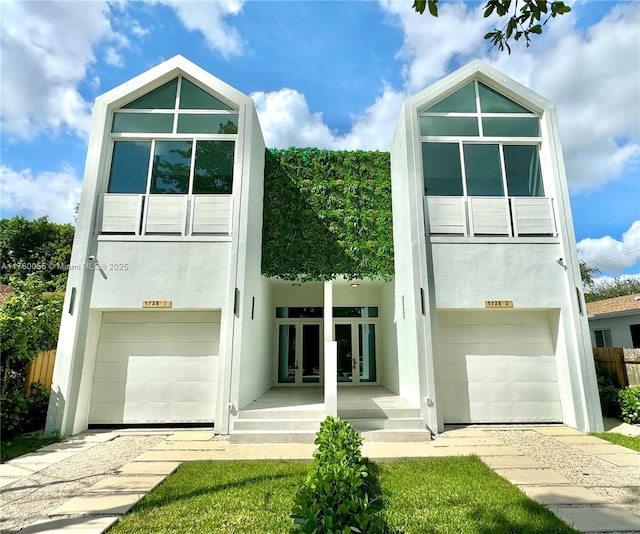 view of front facade with french doors, a garage, and stucco siding