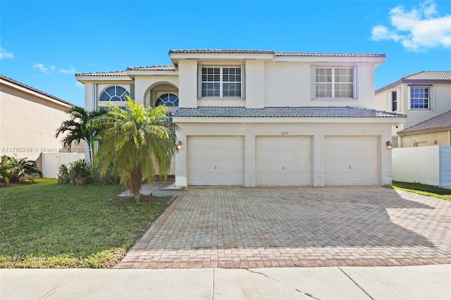 view of front of house with stucco siding, a tile roof, decorative driveway, a front yard, and a garage