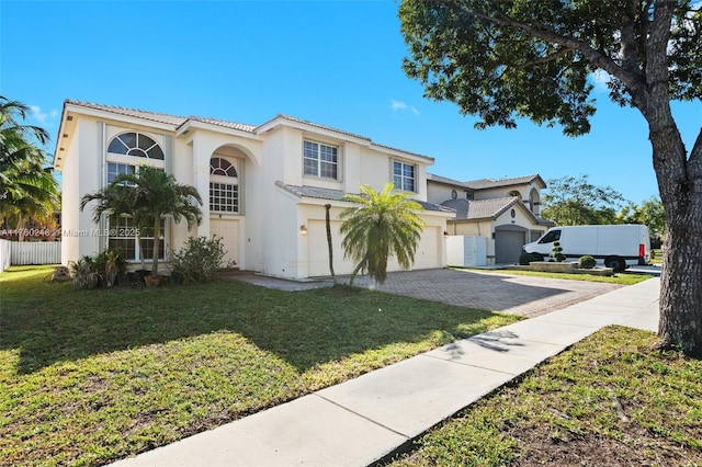 mediterranean / spanish-style house featuring a front yard, fence, an attached garage, a tile roof, and decorative driveway