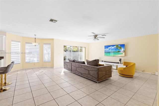 living area featuring light tile patterned floors, visible vents, baseboards, and a ceiling fan