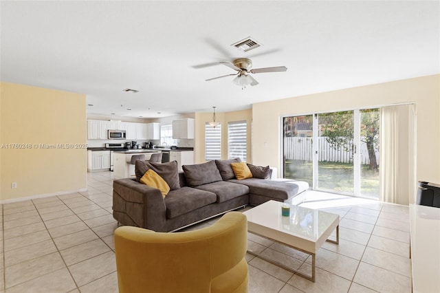 living room with a wealth of natural light, visible vents, a ceiling fan, and light tile patterned floors