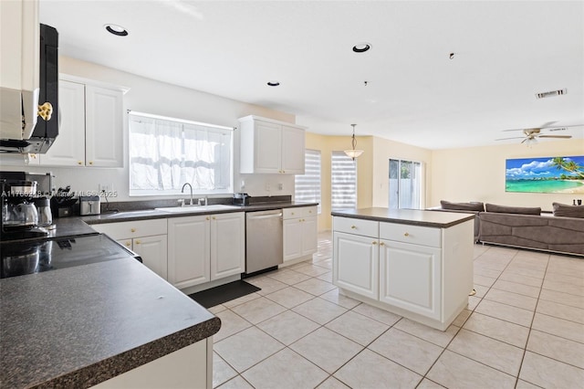 kitchen featuring dark countertops, a sink, light tile patterned floors, and stainless steel dishwasher