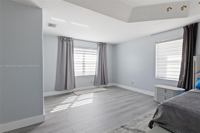 bedroom with light wood-style floors, visible vents, and baseboards