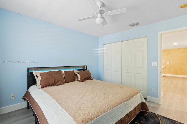 bedroom featuring visible vents, a ceiling fan, wood finished floors, a closet, and baseboards