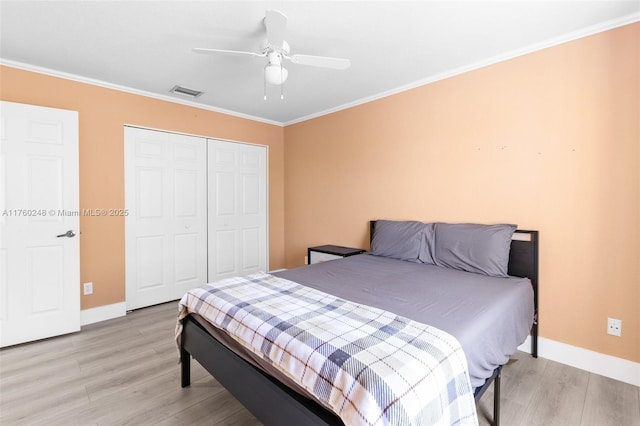 bedroom featuring a closet, visible vents, light wood-type flooring, and crown molding