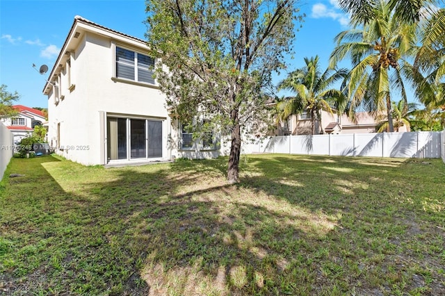 back of house featuring stucco siding, a yard, and a fenced backyard