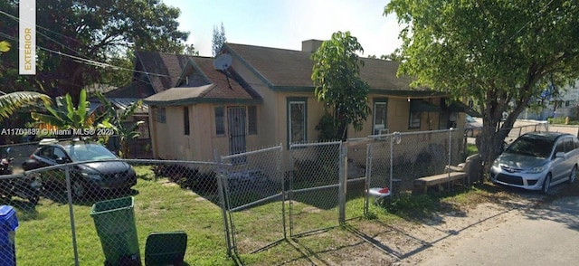 view of front facade with a fenced front yard, a front lawn, and stucco siding