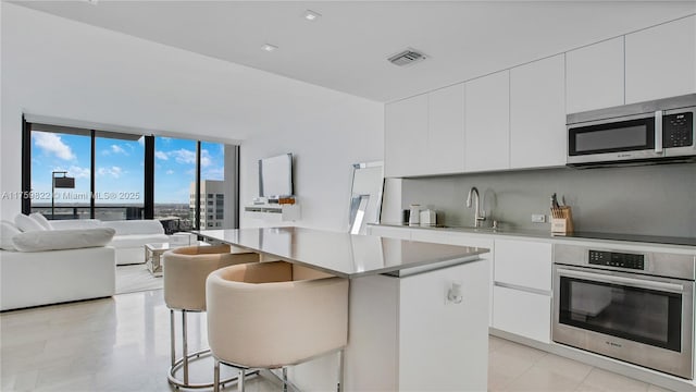 88 SW 7th St Unit 2208, Miami, FL 33130 - kitchen with stainless steel appliances, a kitchen island, open floor plan, and white cabinets